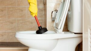 Clogged commercial toilet being serviced by Houston plumbing services